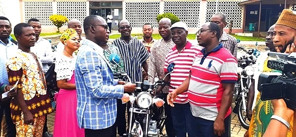 Mr Seth Oduro-Boadu, the MCE (left) presenting one of the motorbikes to an assembly member while others wait for their turn