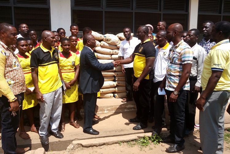 Mr Adusei (in suit) in a handshake with Mr Quaicoo to officially receive the cement bags