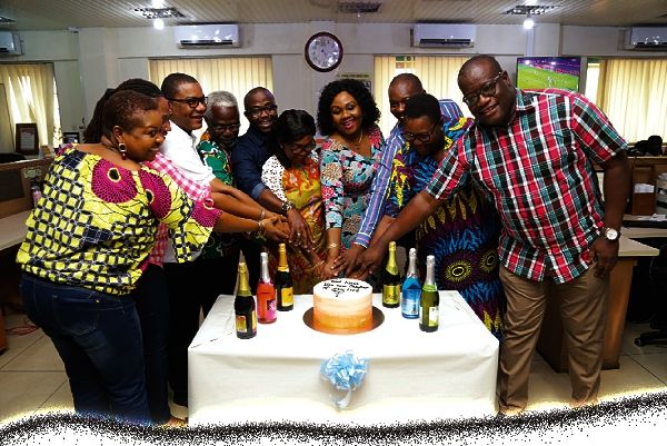 Ms Abigail Bonsu (5th right) being assisted by Mrs Mavis Kitcher, Director, News and some editors to cut a farewell cake