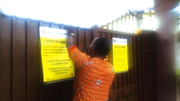 An official fo the Ghana Tourism Authority posting a closure notice to the American Guest House at Adeiso