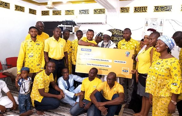 Abubakar Mohammed presenting the dummy cheque to the Chief Imam, Sheikh Osmanu Nuhu Sharubutu, while some staff of MTN look on