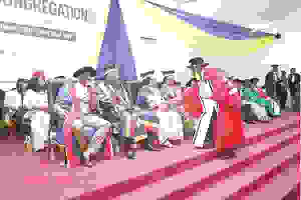 Mrs Nancy Thompson, Chairperson of the UCC Governing Council,  in a handshake with a PhD graduate 