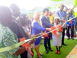 Prof. Lihua (5th left) being assisted by Dr Gidisu (2nd left) and Mr Richard Arku, DCE for North Tongu (right, in smock), and other officials to cut the tape to inaugurate the hospital 