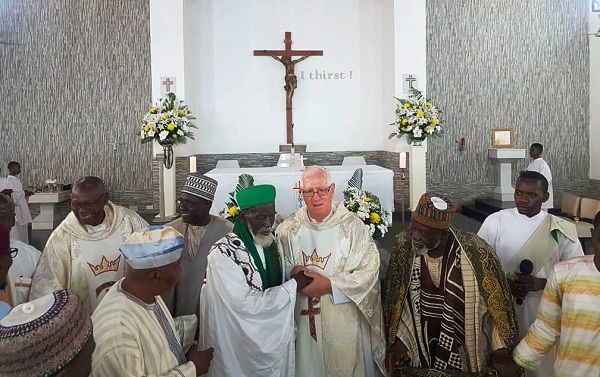 Dr Sheikh Nuhu Sharubutu (3rd left), the Chief Imam, in a handshake with Father Andrew Cambell, Priest of Christ the King Parish