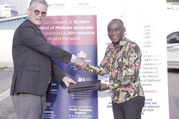 Mr Kingsley Agyeman, the Registrar of the Scholarship Secretariat, (left) exchange notes with Mr Christopher Sauer, Executive Director of International Growth and Strategy of the St George University School of Medicine