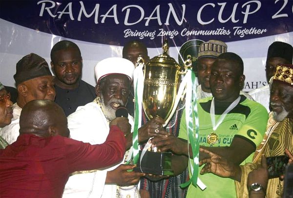 Sheikh Osman Nuhu Sharubutu (left) presenting the trophy to the captain of Nima
