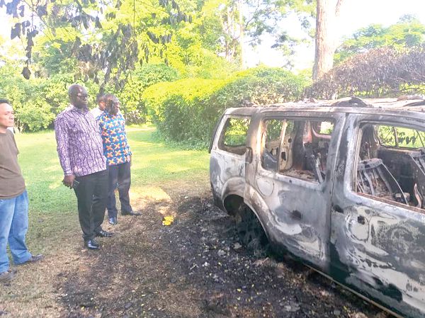 Mr Kwaku Asomah-Cheremeh (2nd left) looking at one of the vehicle burnt by the aggrieved workers