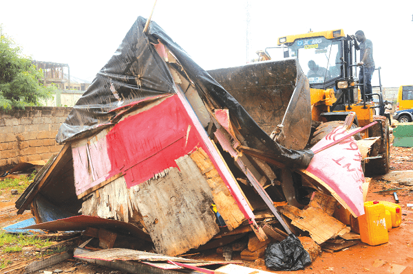 A bulldozer demolishing an unauthorised wooden structure along the motorway