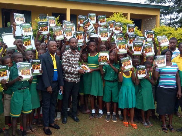  Mr Patrick Kojo Yamoah presenting the exercise books to the pupils 