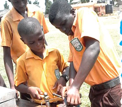 It was Basic Design and Technology (BDT) period for the Form Two students of the Kaneshie Awudome ‘3’ Junior High School in Accra. Here, Robert Adu Ansah with hammer in hand and Kwabena Okyere tries to bend  the rod they were using to fix the seat of a broken chair. Looking on from behind is their mate, Benjamin Agyekum Amoah. Picture:  LYDIA ESSEL-MENSAH