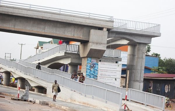 Some pedestrians using the completed footbridge on the Adentan portion of the road
