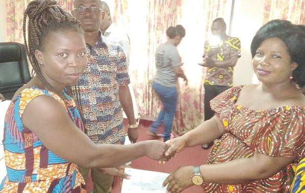 Ms Judith Klutey (right), member of the community presenting a cheque to Mansa Tettevi  from the Adaklu Constituency