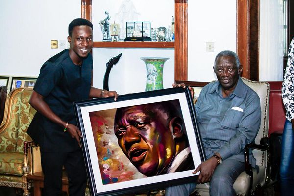 Daniel Arthur (left) presenting one of his works to former President John  Agyekum Kufuor