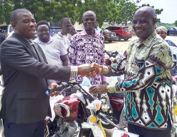 Mr Adzoteye Lawer Akrofi (right), the DCE for Ada West, handing over the key of a motorbike to Mr David Narh Amuyao, the Presiding Member of the Assembly