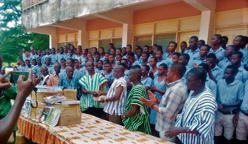 Mr Ayeriga Azeriya, the organising secretary of the ‘89 year group, presenting the textbooks to Mr Ababu Afelibeik  (front row fourth from right), the headmaster of the school
