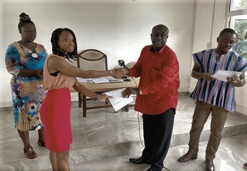 Mr Joseph Kwasi Asuming (2nd right) the DCE, presenting the scholarship letter to Miss Judith Nana Serwaa