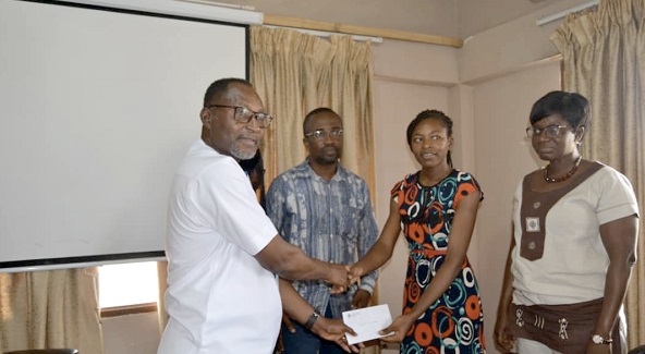 Mr Daniel Adumuah (left) presenting a package to one of the beneficiaries, Ms Deborah Joy Nyarko, while Mrs Lilian Baeka (right), the Planning Officer of the assembly and Mr Perry Ofori, the officer in charge of Supervision and Monitoring at the Municipal Education directorate look on