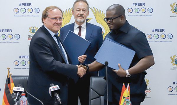  Mr Charles Adu Boahen (right) exchange pleasantries with Dr Stefan Oswald after signing the agreement. With them is Mr Christoph Retzlaff (middle), the German Ambassador to Ghana