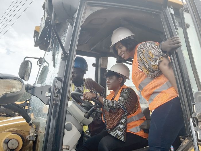 Ms Adwoa Safo (right) and Ms Janet Tulasi Mensah (middle) onboard the heavy machine during the sod cutting ceremony