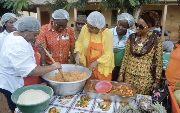 Mrs Cynthia Morrison (3rd left) being assisted by Dr Mrs Gertrude Quashigah (left), the acting National Coordinator of the Ghana School Feeding Programme, to prepare the 'gari fotor. Looking on is Dr Afisah Zakaria (right), the Chief Director of the Gender Ministry
