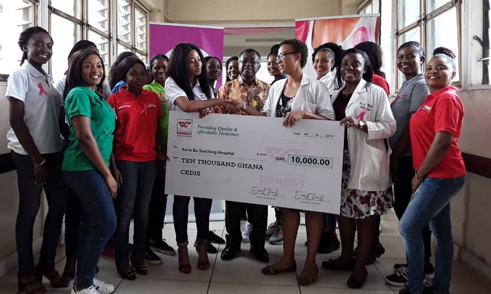 Ms Sharon Anim (left), Brands Communications Manager of Ernest Chemists Limited, presenting the cheque to Dr Florence Dedey, the Head of the Breast Unit of Korle-Bu Teaching Hospital, while Professor J.N. Clegg-Lampte and Dr Josephine Nsaful (3rd right) assisting her. Looking on are the 2019 contestants of Ghana's Most Beautiful 