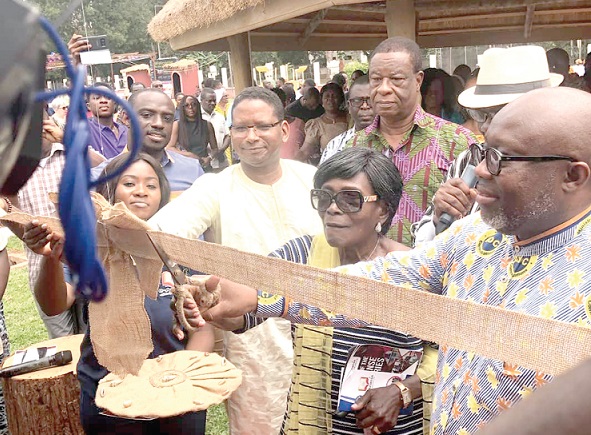 Mr George Andah (right) being assisted by other dignitaries to cut the tape to open the Legon branch of E-ananse library.