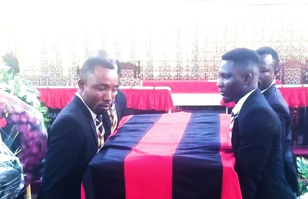 Kakra Essamuah (hand raised), twin brother of Colin Essamuah, with other family members at the burial service