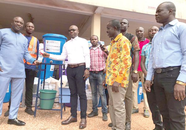  Mr John Kofi Donyina (left) receiving the items from Mr Kwadwo Obeng Aboagye. Those with them are staff of the assembly and Ghana Nuts