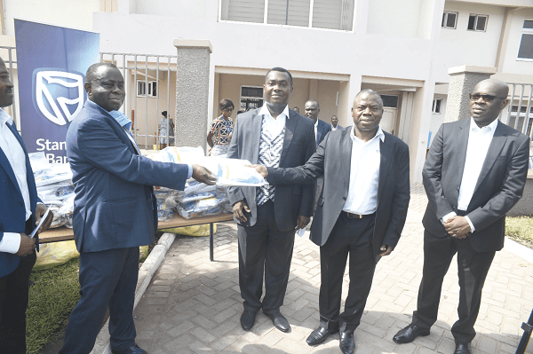  Mawuko Afadzinu (2nd-right) being assisted by Mr Alhassan Andani (right) to hand over the items to Dr Daniel Asare, the Chief Executive Officer of Korle Bu