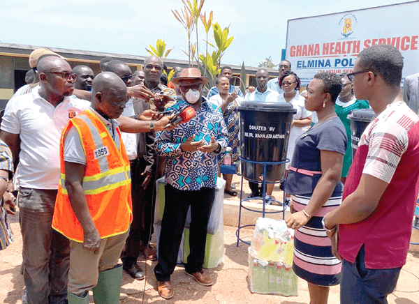 Dr Ato Arthur (in mask) presenting items to Mrs Ampah Bryant (right)