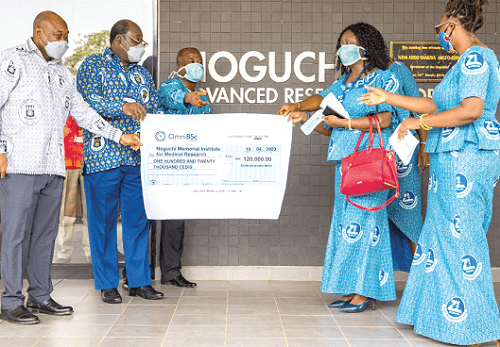 Mrs Adokarley Okpoti-Paulo, the Director of Finance of Zoomlion Ghana Limited (second right), being assisted by Ms Lissah (right) to present the dummy cheque to Professors Anang (second left) and Awandare (left)