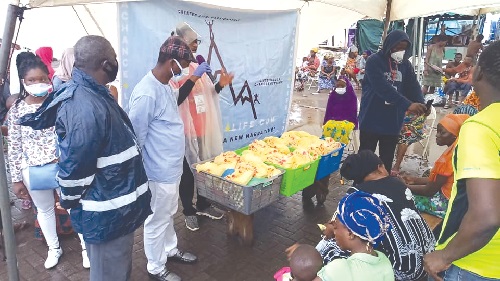 Dr Kofi Osei-Acheampong (right with microphone) praying over the food before distribution