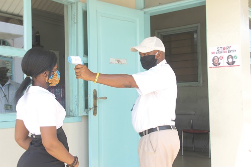 A security officer at the Graphic Communications Group Limited (GCGL) taking the temperature of a client before access to the Graphic premises. Picture: EDNA SALVO-KOTEY