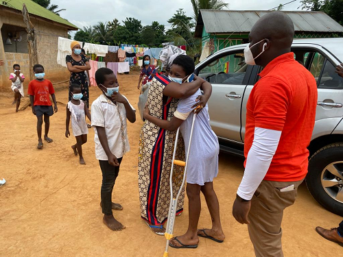 Rita Owusu (in clutches) meets her mother after months of being away in the hospital. Looking on is Rev Amaris Nana Adjei Perbi (in red and white), the Lead of Vodafone Ghana Foundation, who led the team that drove Rita home.