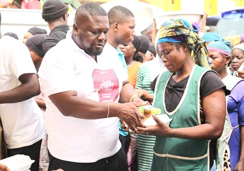 Mr Owiredu Wadie, CEO of KBK Foundation, shares food with the Kayayei