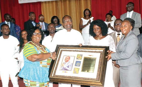 Mrs Vivian Adom Nyarko (left), wife of the Senior Pastor of the End-Time Revival Centre, presenting a citation to Mr Affail Monney (2nd left) during the service. Those looking on include Mrs Elizabeth Naakoh Monney (2nd right), wife of the celebrant, and some members of the church.