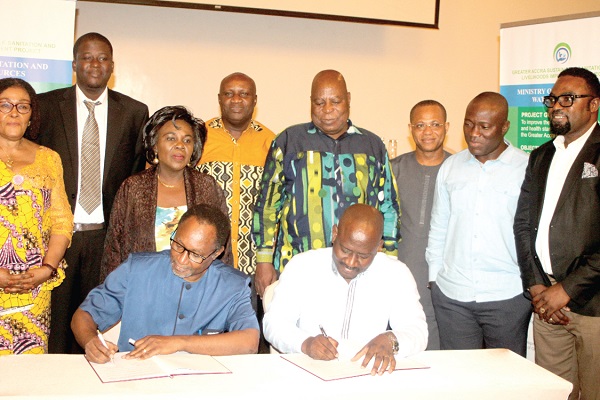 Mr Nii-Noi Adumuah (left),  and Mr Noah Tumfo (right), signing the agreement in Accra. Those with them include Ms Cecilia Dapaah (3rd left),  Mr Ismael Ashietey (4th right) and other officials. Picture: GABRIEL AHIABOR
