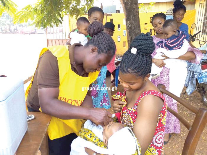 Ms Leticia Boahemaa (left) immunising a child in Sunyani, while others wait for their turn 