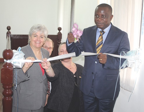Mr Dominic Nitiwul (right), the Minister of Defence, being assisted by Ms Stephanie Sulivan (left), the US Ambassador to Ghana, and Ms Kirsten Madison (partly covered ), the Assistant Secretary of the US Department of State, to cut the tape to inaugurate the National Border Fusion Centre in Accra.