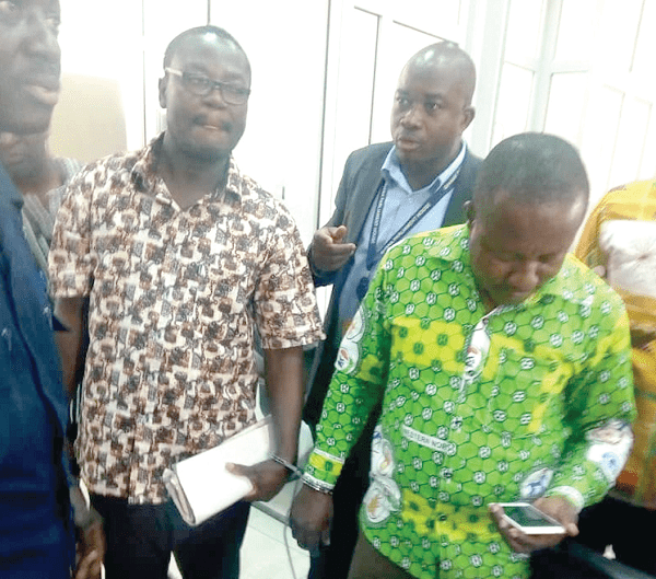 Isaac Akowuah (left), former District Finance Officer, and James Esilfie, the current officer, in handcuffs
