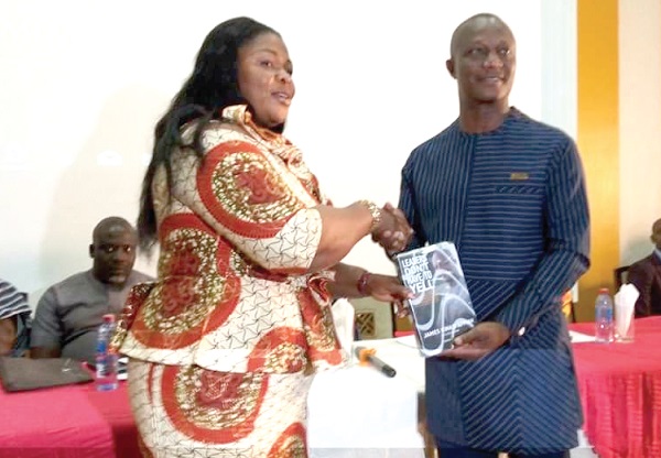 Coach Appiah presenting a copy of his book to Mrs Evelyn Kumi-Richardson