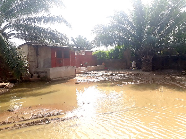 The barricaded portion of the gutter with blocks is making it impossible for any drainage from nearby to enter, causing water to spill onto the main road