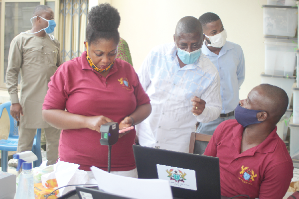 Mr Samuel Tettey (2nd right), Deputy Chairman of the Electoral Commission  in charge of Operations, observing the pilot registration process at Amasaman. Those with him include Ms Victoria Boateng (left) and Mr Joseph Obeng Ntim (right), both staff of the EC. Picture: GABRIEL AHIABOR