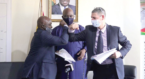 Mr Yaw Owusu (left) Deputy CEO, Ghana Railways Development Authority, doing the COVID-19 greeting with Mr Nadav Simhoni, Managing Director, Amandi Holdings Limited, after the signing ceremony. Looking on is Mr Joe Ghartey, the Minister of Railways Development.