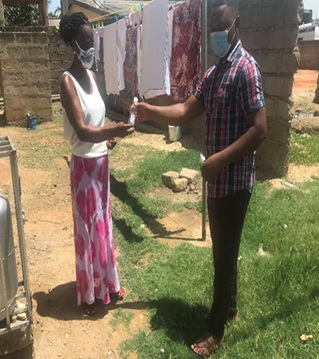 Presentation and use of hand sanitizer to a lady at Adidome, Central Tongu District