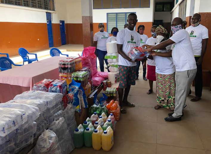   Madam Georgina Boateng, Country Director of STACAN presenting the items to Isaac Quansah a student of the school. 
