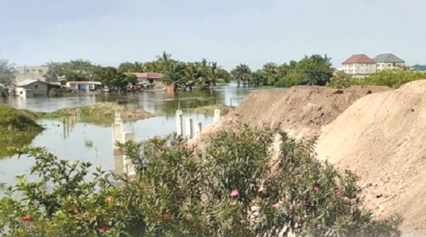 A developer filling the path that carries water spilled from the Weija Dam with heaps of sand at Tetegu in Accra 