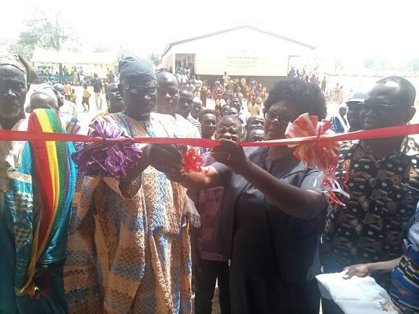 Ms Theresa Baveng(2nd right) being assisted by a representative of the Kpachi-Lana, Abdulai Laryo to cut the tape to inaugurate the project 
