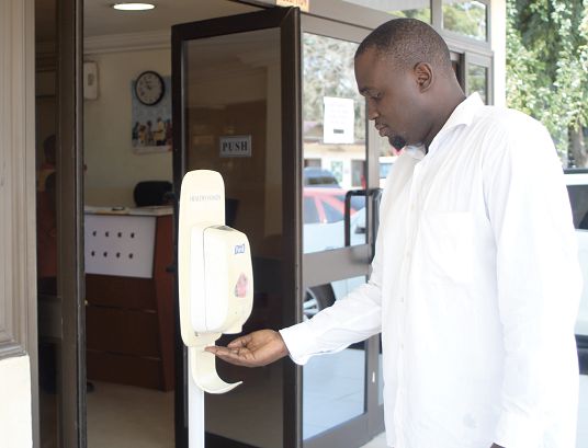  A staff of the Ministry of Energy using the hand sanitiser at the entrance of the office in Accra. Picture: GABRIEL AHIABOR