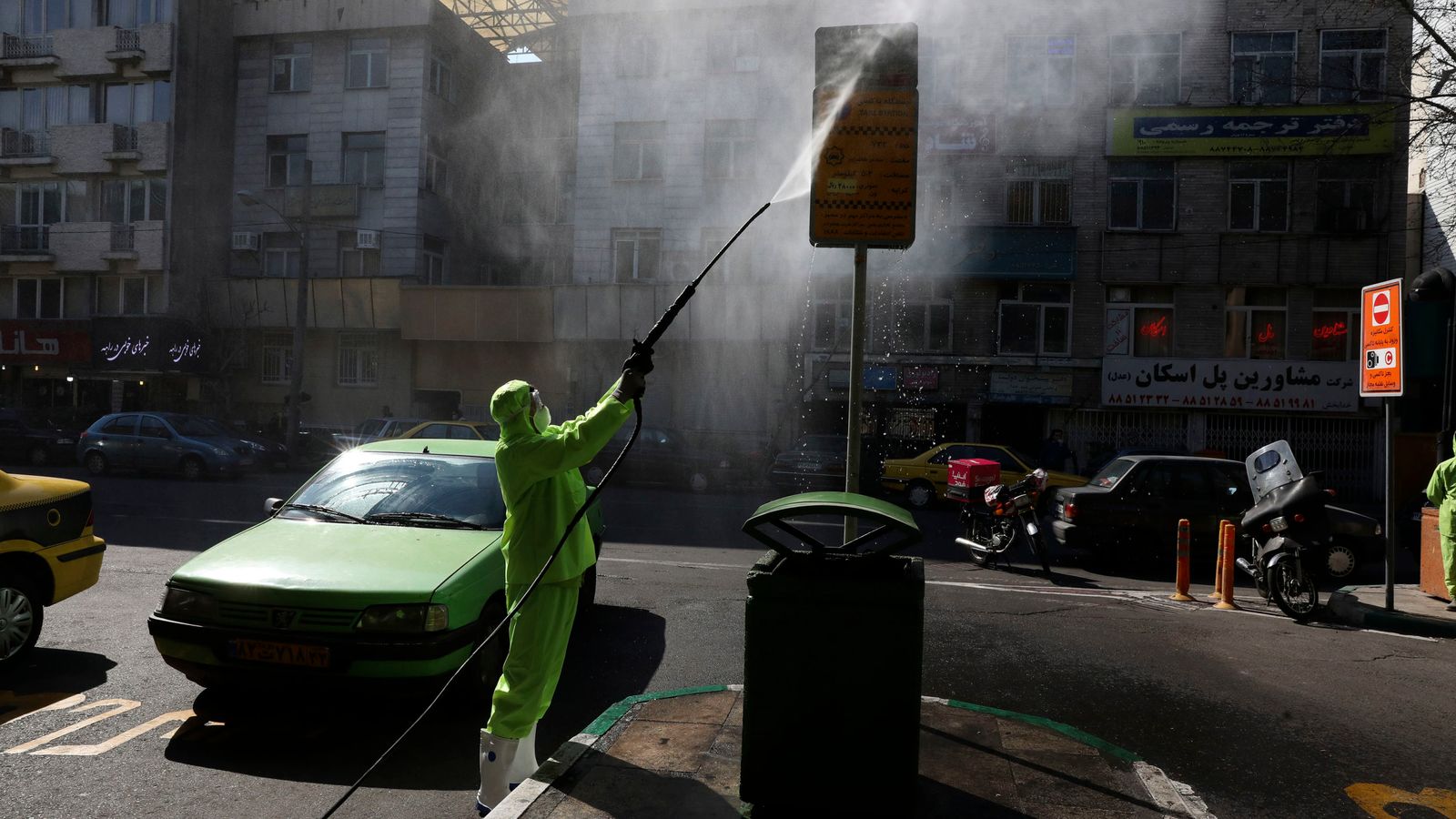A city worker disinfects a bus stop sign during the coronavirus outbreak in Iran